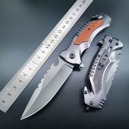 Open multifunctional folding knife next to a metal ruler with closed version on dark background