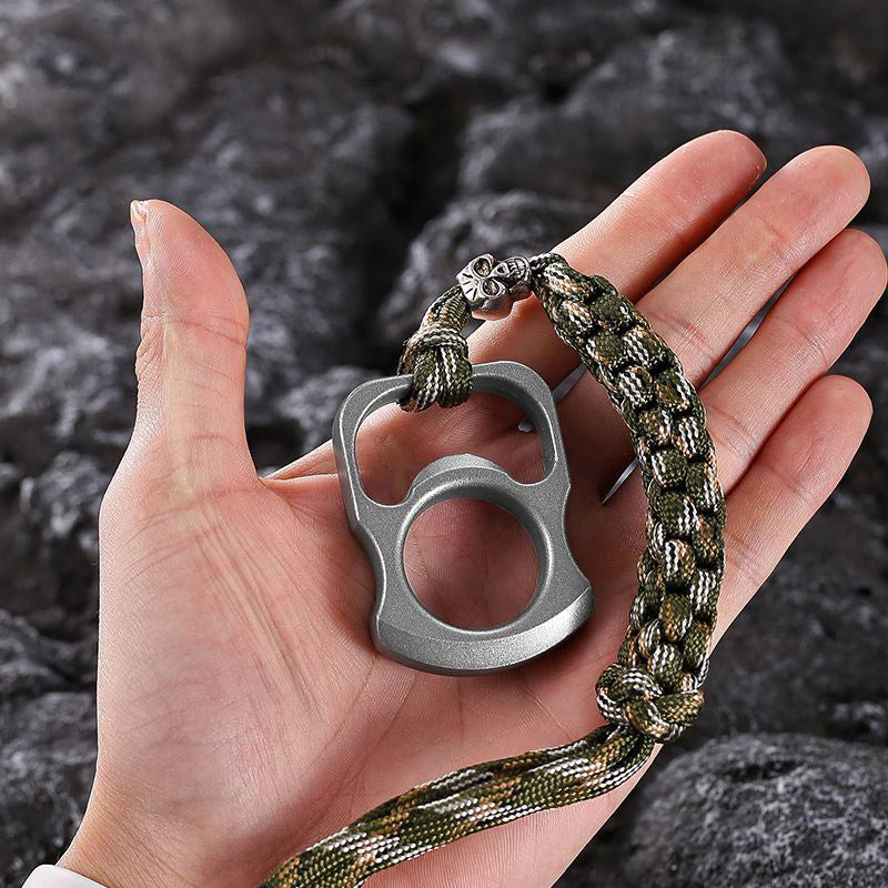 Open palm holding the zinc alloy opener tool with a braided camouflage paracord lanyard attached