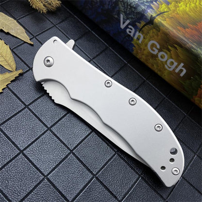 Closed folding knife with contoured all-steel handle and hex screws beside a colourful printed box