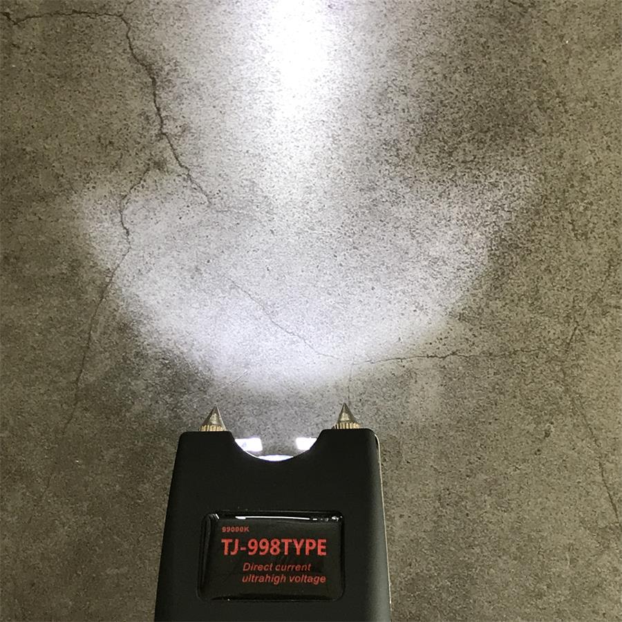 Close view of the black unit head with a bright LED beam cast on concrete and the red TJ-998TYPE label panel below the twin pins