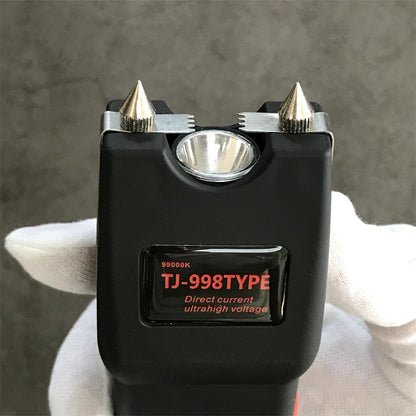 White gloved hand holding the black unit head with cone electrode pins on serrated chrome strips and the glossy TJ-998TYPE label