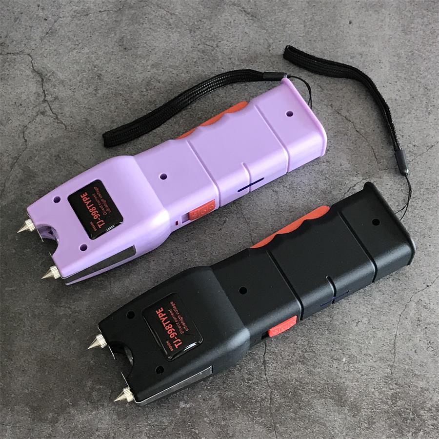 Light purple and black 998 stun gun units lying diagonally on gray slate with twin electrode pins and red side switches