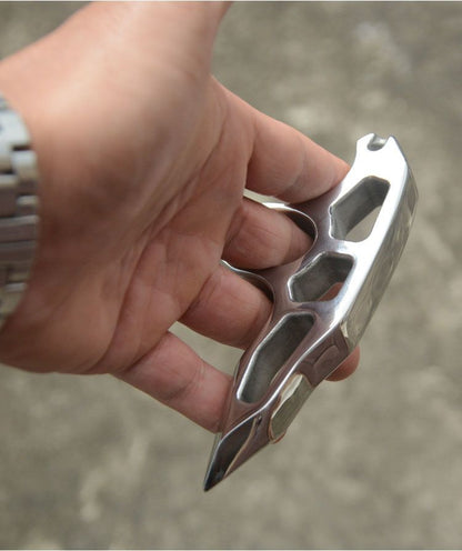 Overhead view of a relaxed hand gripping the steel single-hole knuckle duster with a finger through the hole