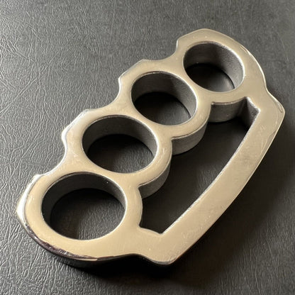 Top-down view of the bare stainless steel parachute rope knuckle duster on black leather.