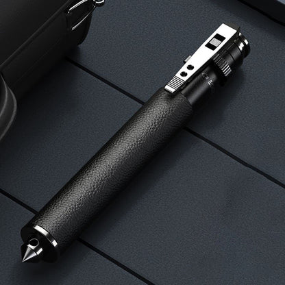 Close-up of the closed baton showing a leather-grain black handle, silver clip and pointed window-breaker tip on a blue quilted surface