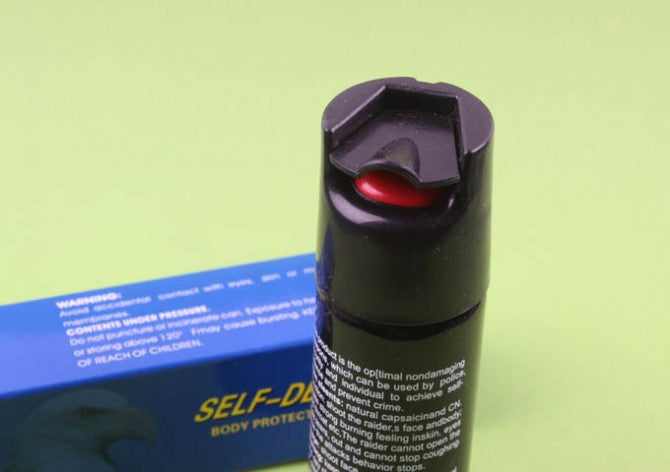 Close-up of pepper spray canister flip-top cap and red nozzle