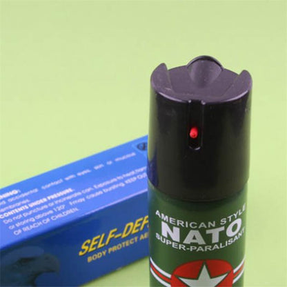 Close-up of the black flip-top safety cap and red actuator on the green pepper spray can