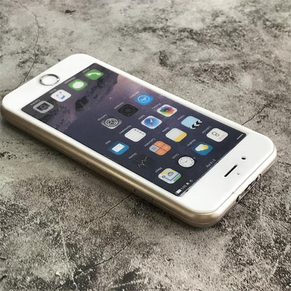 Gold phone-shaped device lying on gray concrete with the printed app-icon screen face up and the twin metal prongs at the near edge