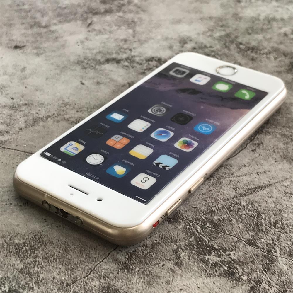 Gold phone-shaped device at an angle on gray concrete showing the printed app-icon face, gold frame and twin metal prongs on the edge