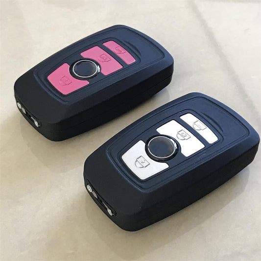 Pink and silver car key stun guns lying side by side showing the matching key fob buttons and the pin electrodes at the end of each unit
