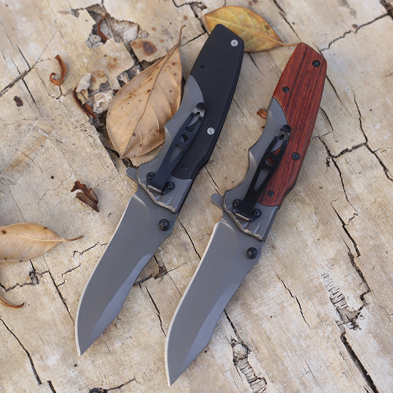 Back view of G10 and wood handle folding knives, pocket clips visible along the handle backs