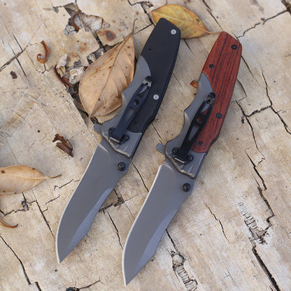 Back view of G10 and wood handle folding knives, pocket clips visible along the handle backs