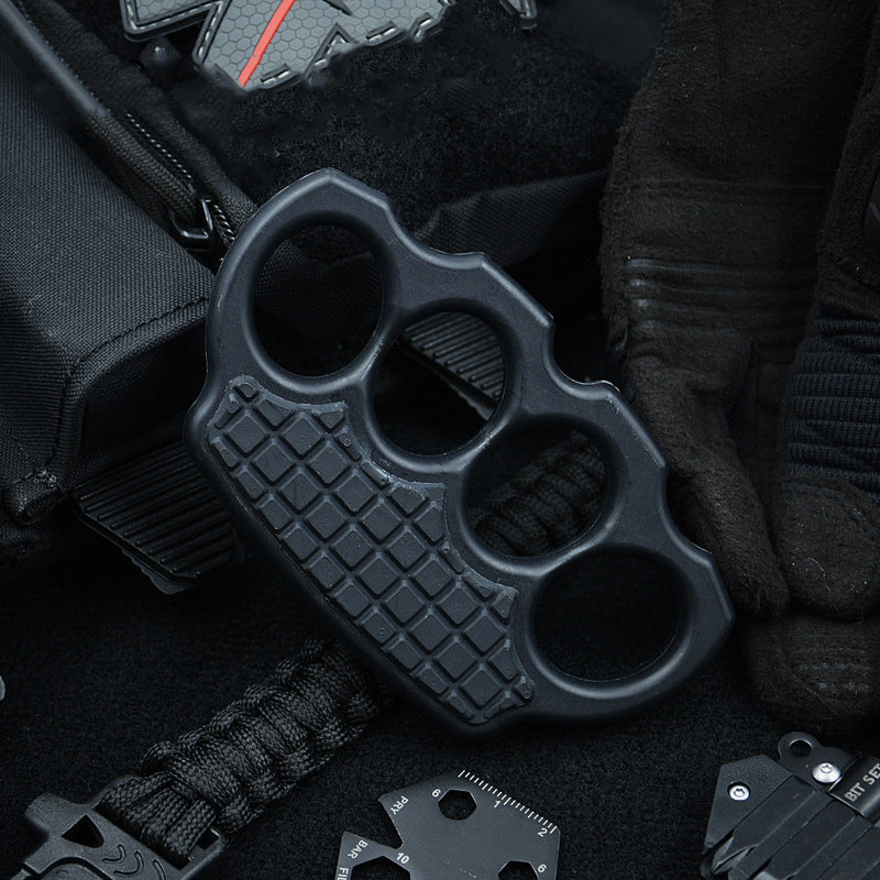 Black knuckle duster arranged in an EDC flat lay with a backpack, paracord and a multitool card