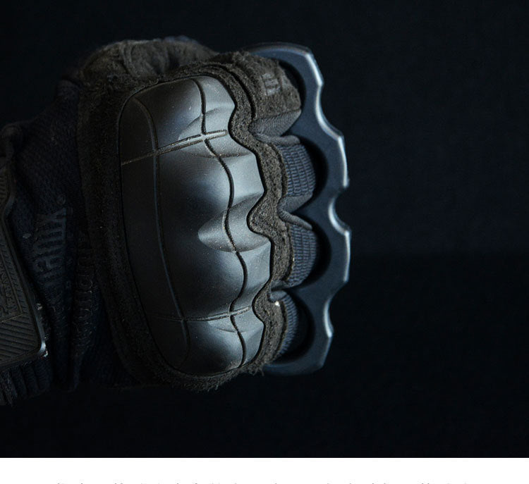 Gloved fist wearing the black polymer knuckle duster with the finger holes seated around the knuckles