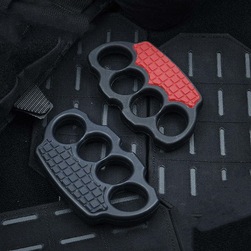Black and red-black knuckle dusters resting side by side on a black MOLLE panel
