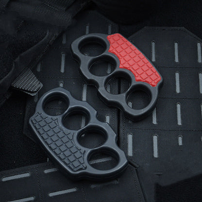 Black and red-black knuckle dusters resting side by side on a black MOLLE panel