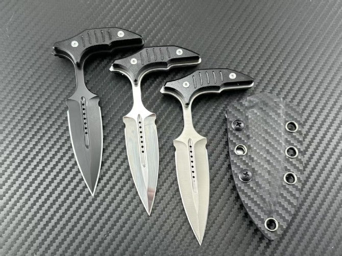 Three push daggers arranged on carbon fiber background showing blade finishes and matching sheath