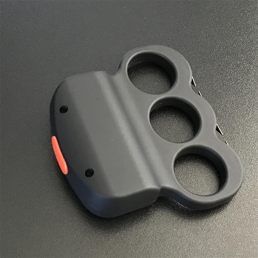 White-gloved hand gripping the black three-hole stun device from behind, USB charging port on the top edge and thin prong plates visible along the left side