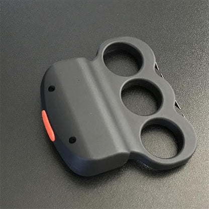 White-gloved hand gripping the black three-hole stun device from behind, USB charging port on the top edge and thin prong plates visible along the left side