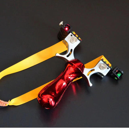 Red slingshot with yellow flat bands and a leather pouch laid on a dark table