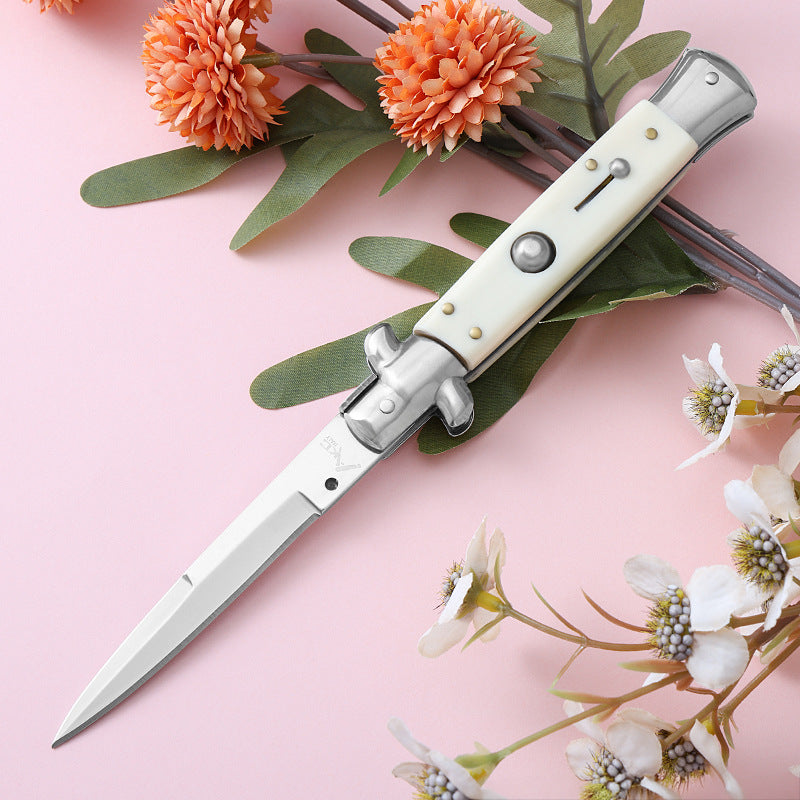 Cream handle folding knife displayed on pink background with flowers