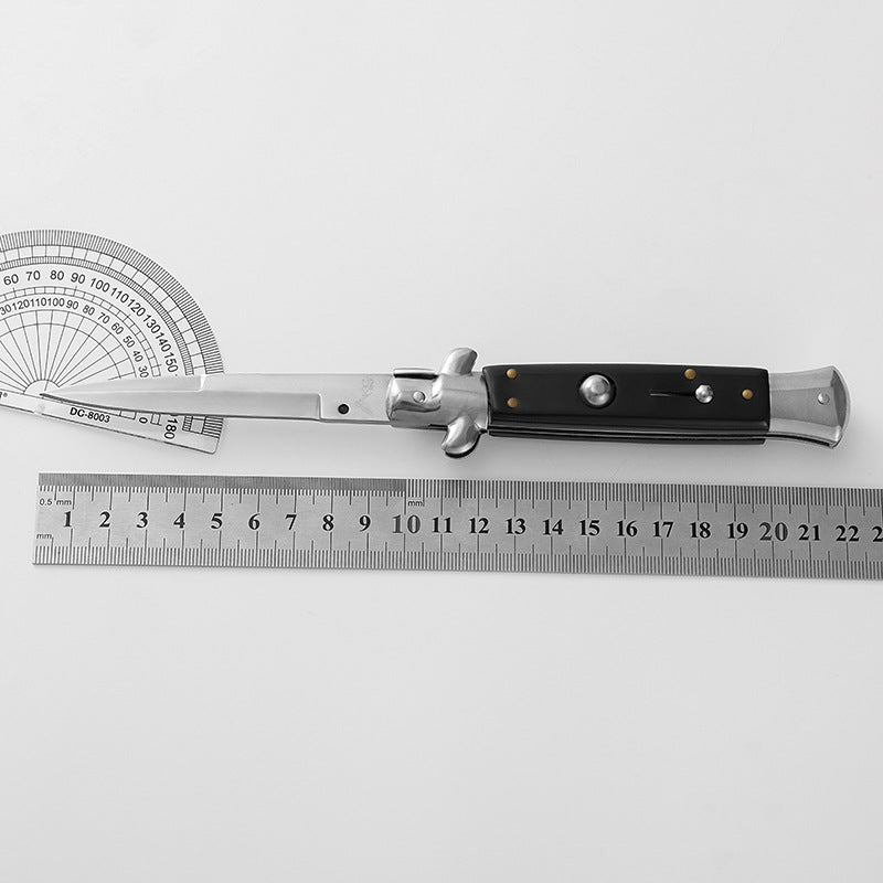 Folding knife laid on protractor and ruler showing blade measurement