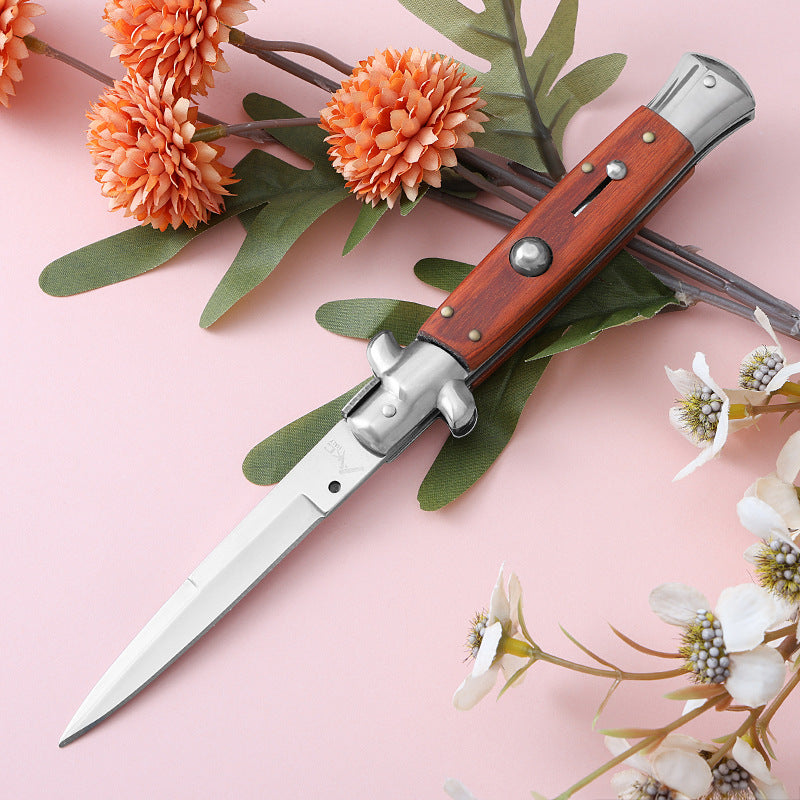 Three colorful folding knives on pink background with orange flowers