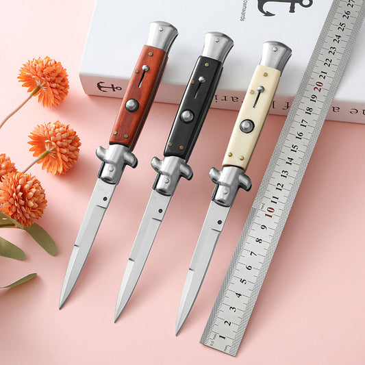 Three folding knives with brown black and cream handles lined up beside ruler
