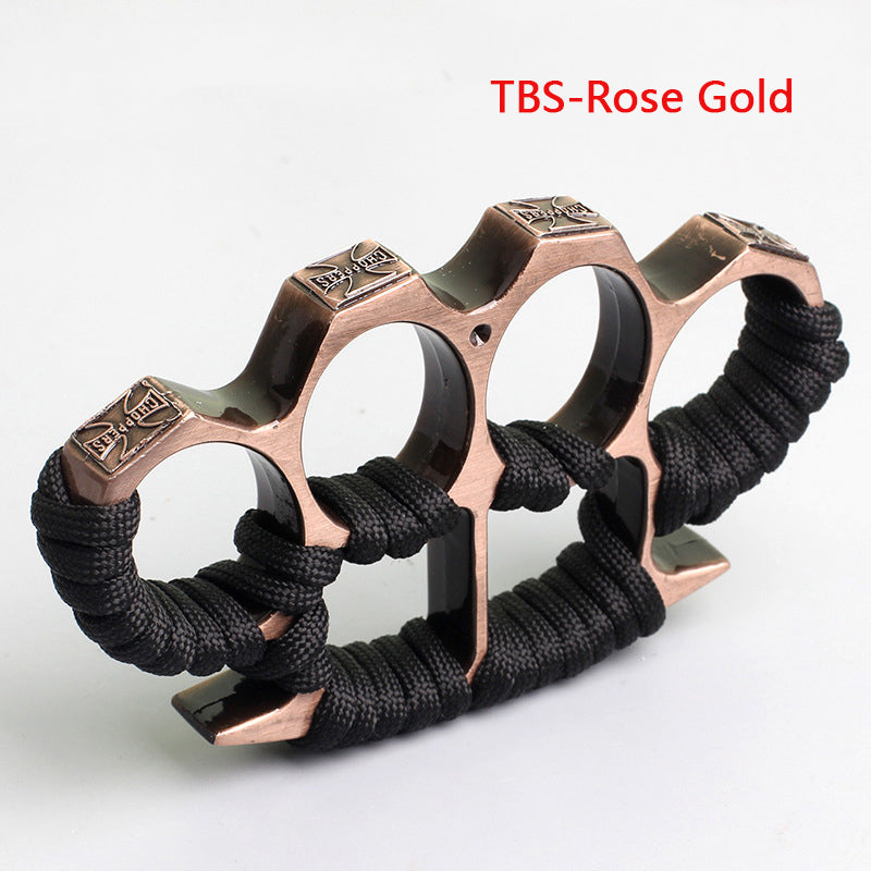 Rose gold three-hole knuckle duster with black paracord grip on white background