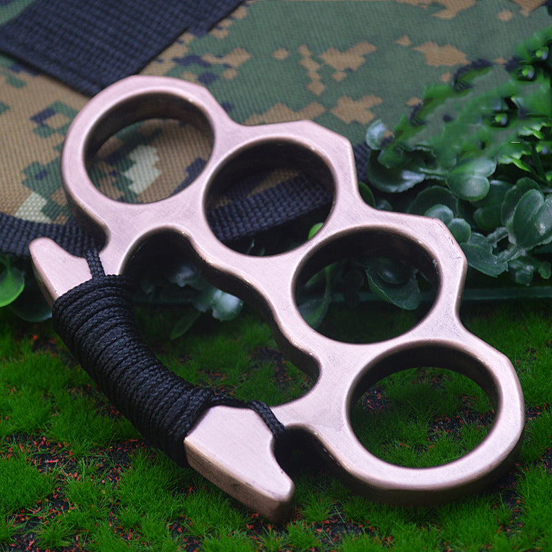 Rose Gold-J aluminum knuckle duster on camouflage fabric and grass