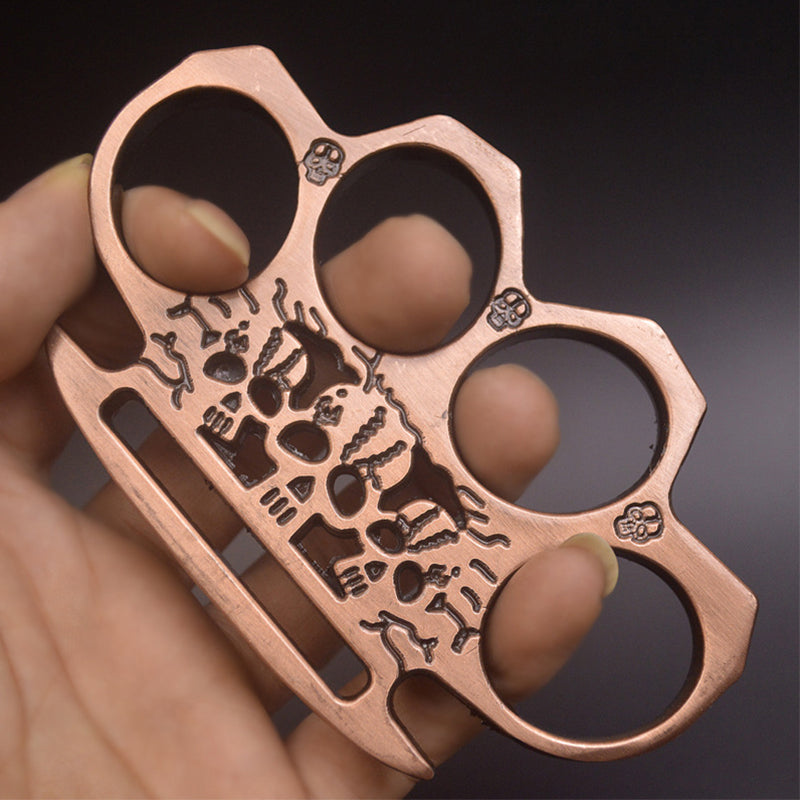 Rose gold skeleton knuckle duster worn on the fingers showing the skull artwork and palm-edge slot