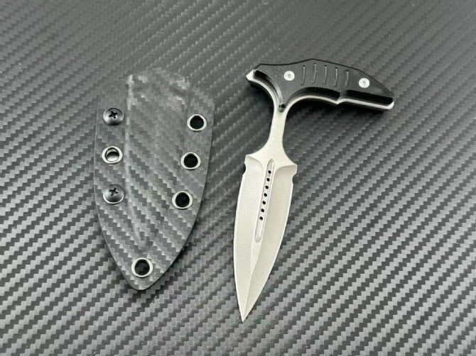 Satin finish push dagger next to its carbon fiber sheath on textured background