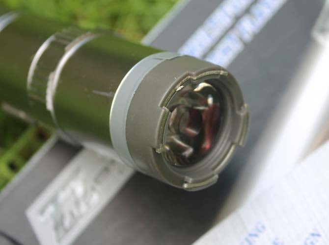 Close-up of the stun gun head showing the central LED lens ringed by small metal contact pins on the crenulated bezel