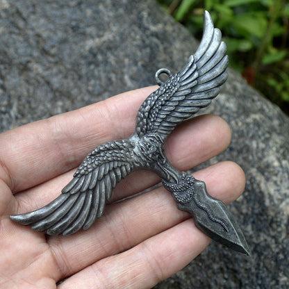 Silver gray eagle pendant held in a hand for scale showing the spread wings and snake wrapped dagger point