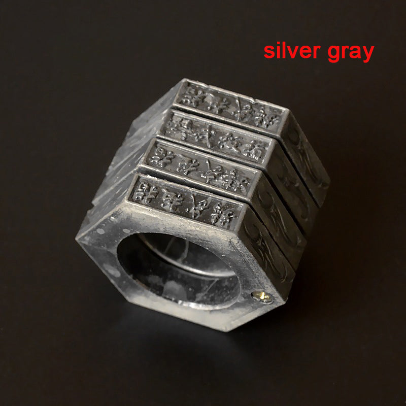 Silver gray hexagon ring built from stacked bands, engraved Chinese characters and flame motifs across the faces, on a dark background
