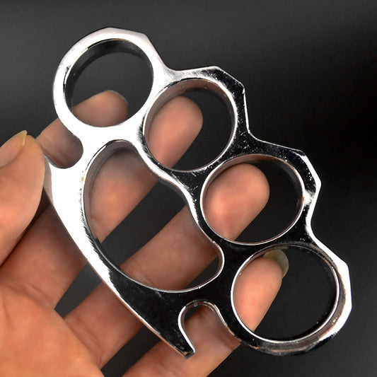 Mirror silver four-hole knuckle duster worn on four fingers showing the wide palm base and finger notch