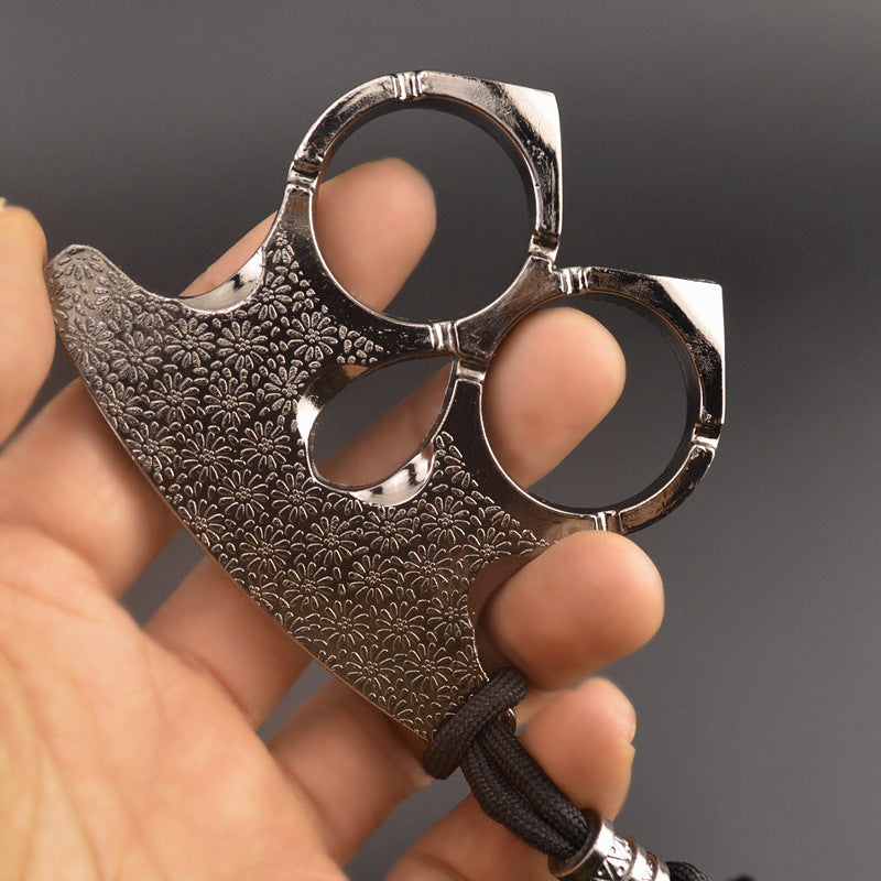 Silver two-finger knuckle held in an open hand with fingers through both rings and thumb in the teardrop opening