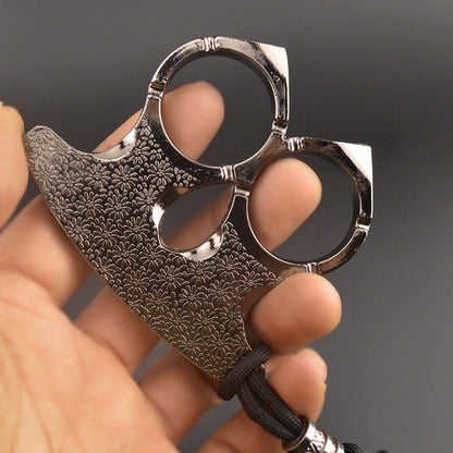 Silver two-finger knuckle held in an open hand with fingers through both rings and thumb in the teardrop opening