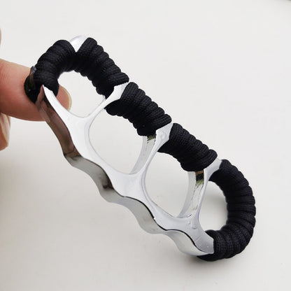 Silver zinc alloy knuckle duster held in hand, black paracord coils along the upper edge