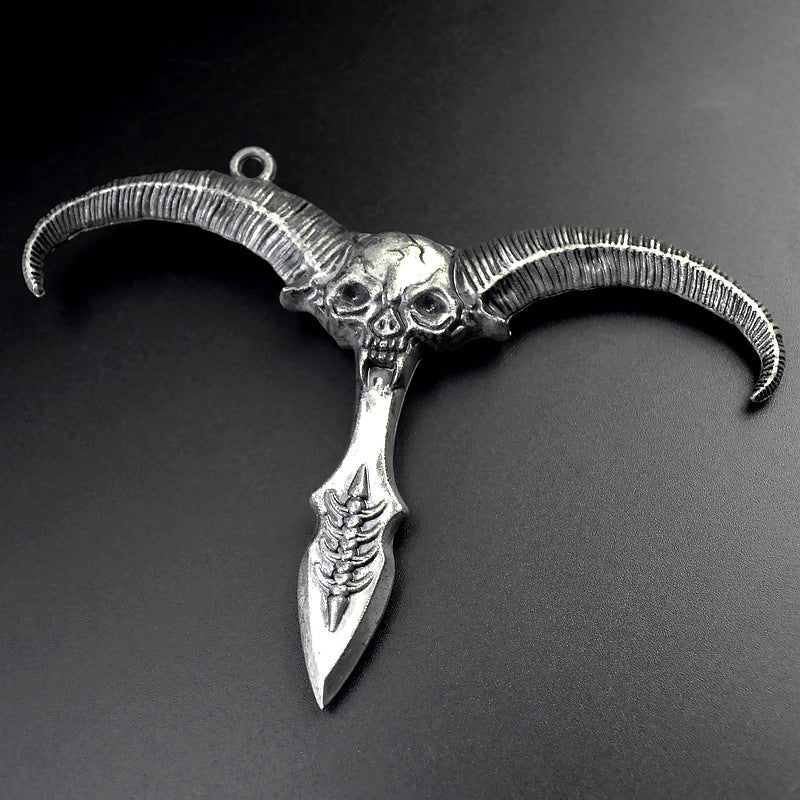 Silver gray sheep skull pendant with ribbed curved horns and a dagger style point on a dark grey background