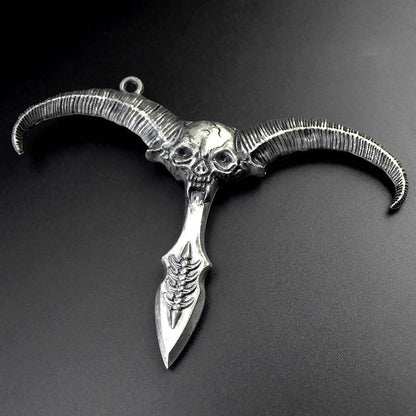 Silver gray sheep skull pendant with ribbed curved horns and a dagger style point on a dark grey background