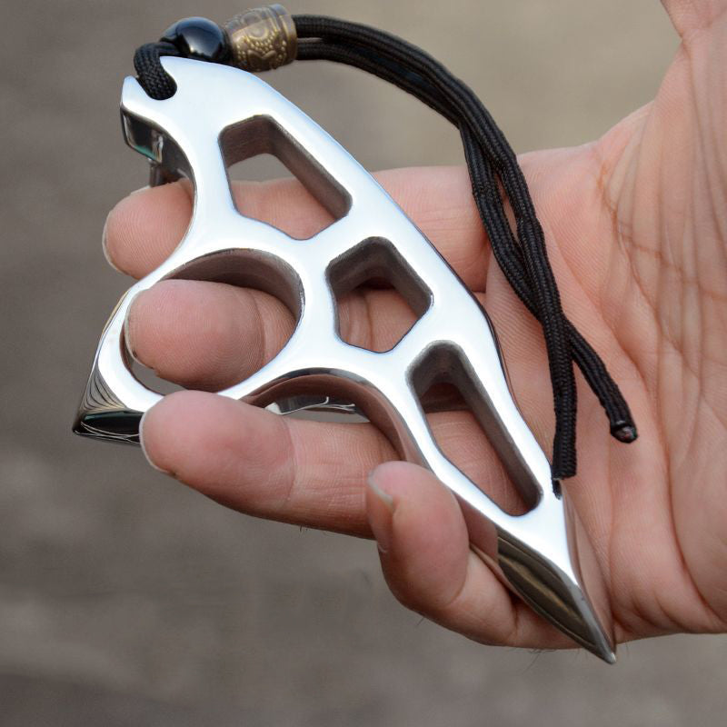 Silver single-hole steel knuckle duster with three angular cutouts and a pointed tip resting on an open palm