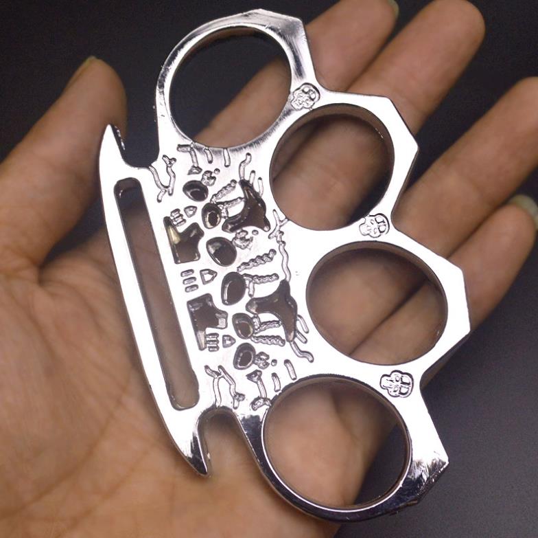Silver skeleton knuckle duster resting in an open palm showing the skull engraving and beveled rim