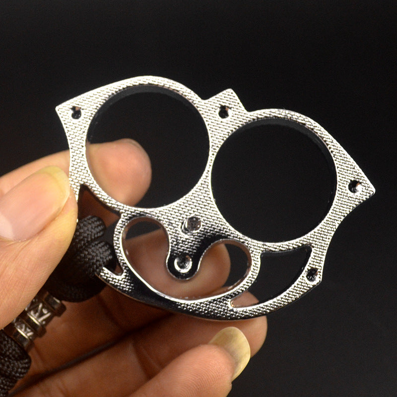Close-up of the silver sloth finger clasp held between fingers showing the knurled face panel, rivet dots and heart-shaped cutout