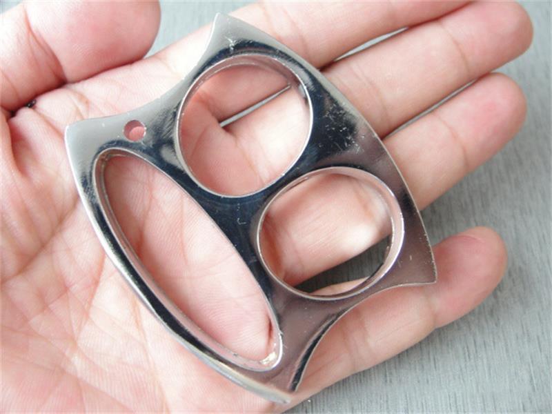 Silver two-hole pocket EDC knuckle duster resting in an open palm, showing the big-mouth monkey profile.