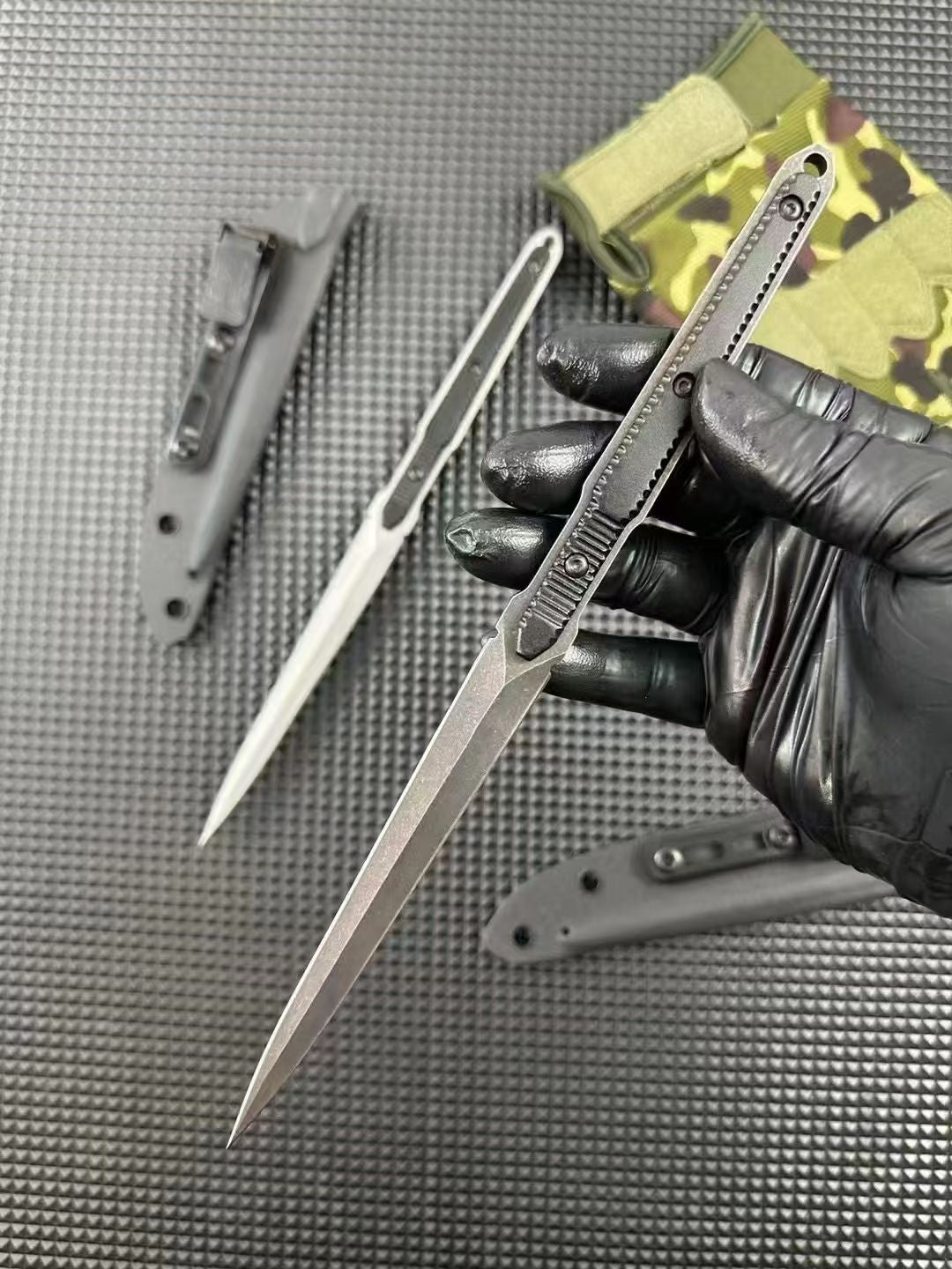 Two bayonets and two clipped sheaths on a pyramid-pattern mat