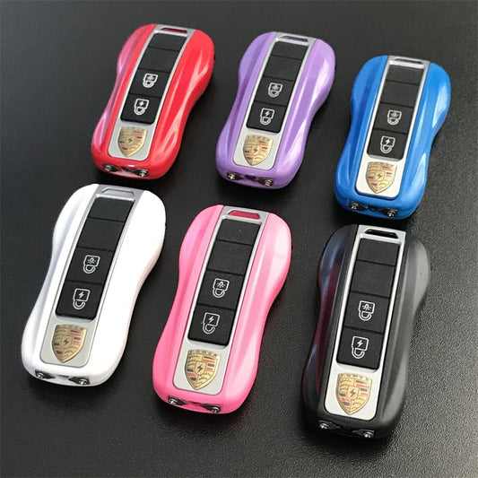 Six car-key style stun gun fobs in red, purple, blue, white, pink and black laid out on a dark surface showing the button panels and gold shield badges