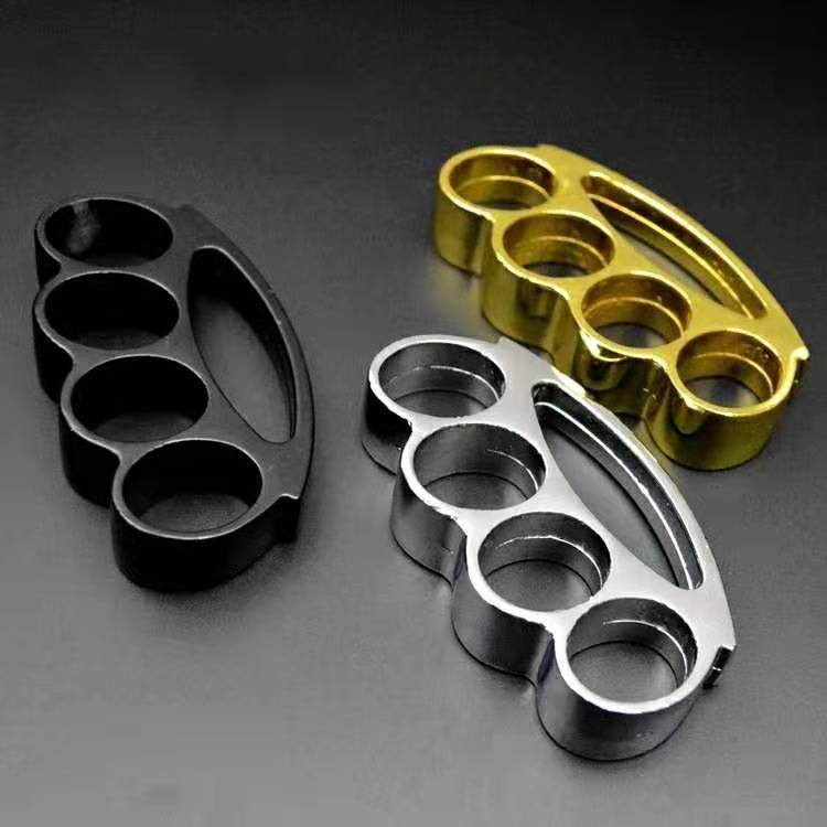 Black, silver and gold smile-hole knuckle dusters arranged on a dark gradient surface
