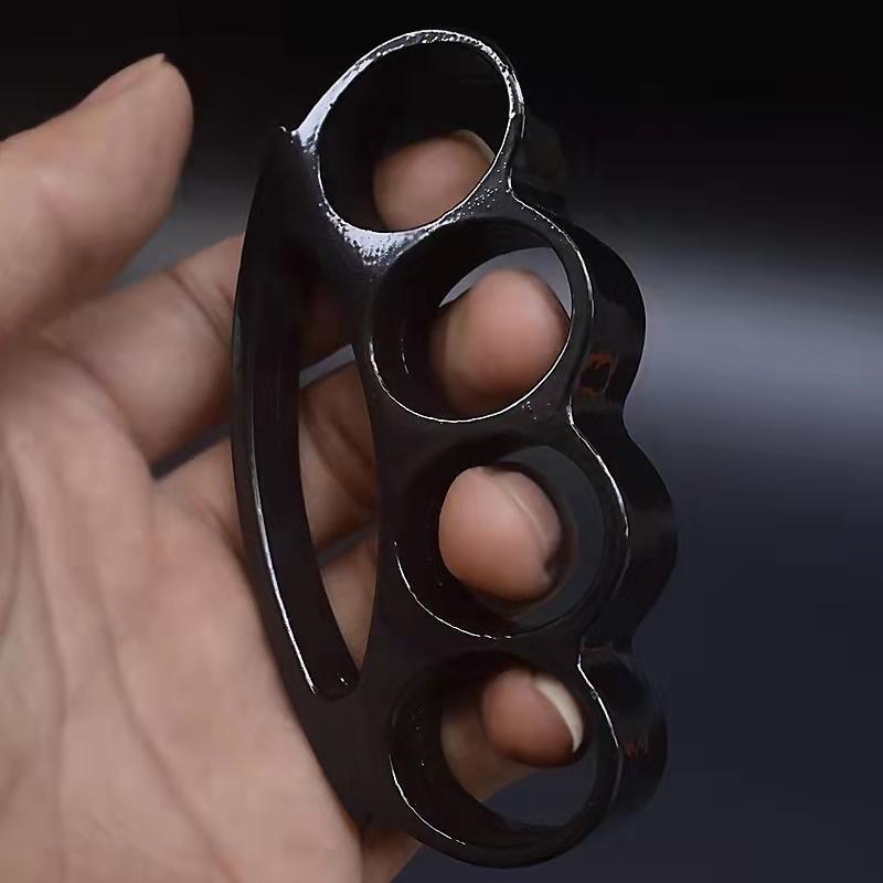 Black smile-hole zinc alloy knuckle duster held in hand showing side profile