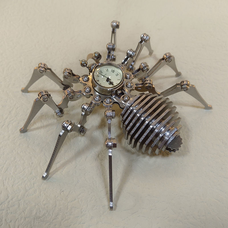 Stainless steel spider desk ornament seen from a raised angle showing the domed clock and leg joints